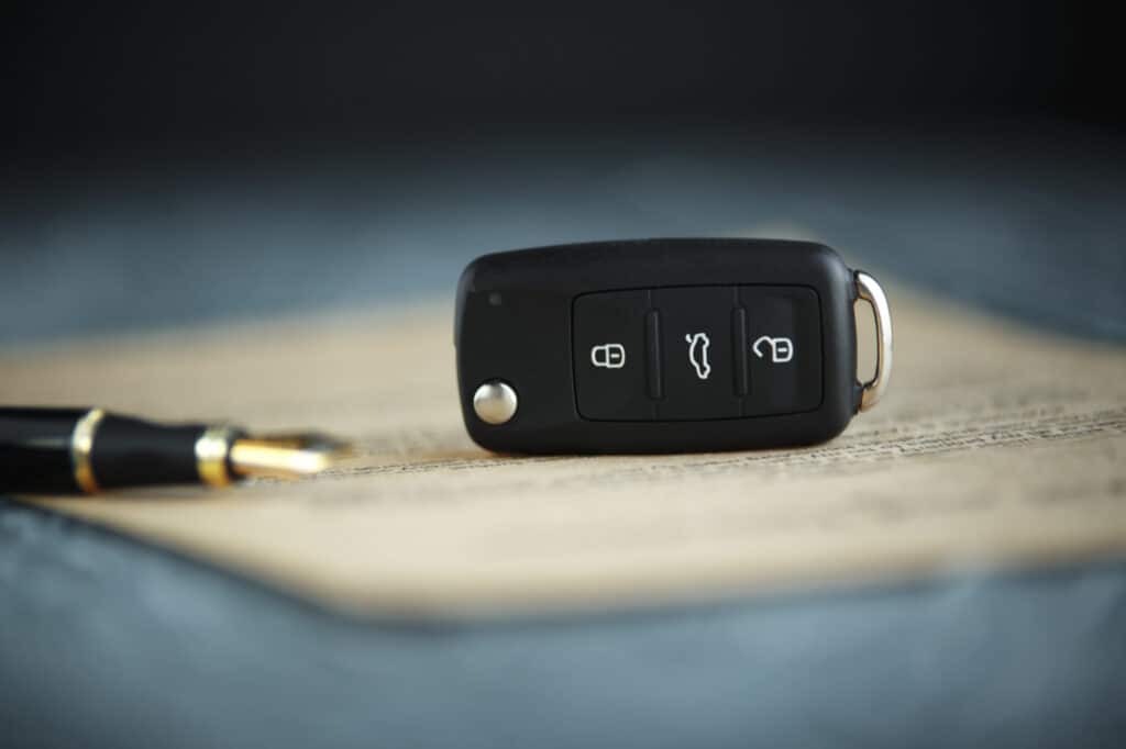Documents Needed to buy a car in australia Close-up of a modern car key fob on a blurred vehicle purchase agreement, with a stylish fountain pen aside, symbolizing the process of buying a car in Australia